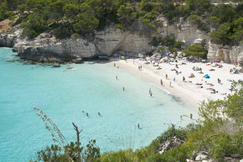 bañistas y aguas cristalinas en Cala Mitjana en Menorca