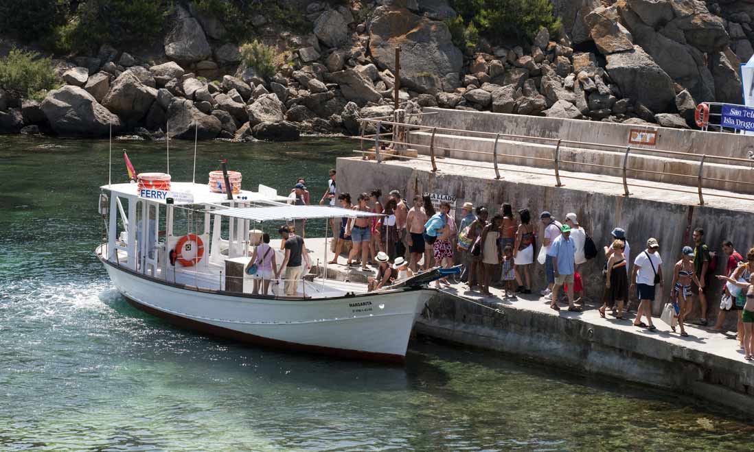 turistas subiendo a los barcos del embarcadero del parque natural de Sa Dragonera en Andrach , Mallorca